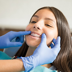 Young girl with braces smiling during dental checkup