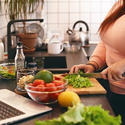 Woman chopping up vegetables in kitchen at home