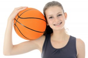 Smiling girl with basketball playing sports with braces