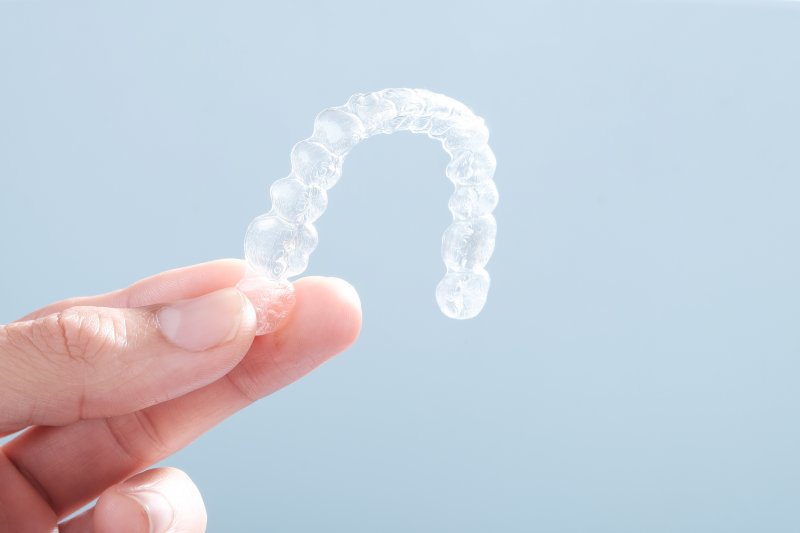 person holding Invisalign clear aligner