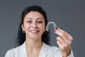 smiling woman holding invisalign