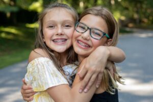 Two young girls with braces smiling and hugging