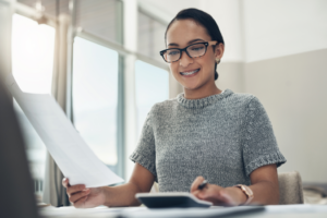 a smiling woman wearing braces and glasses working on a laptop